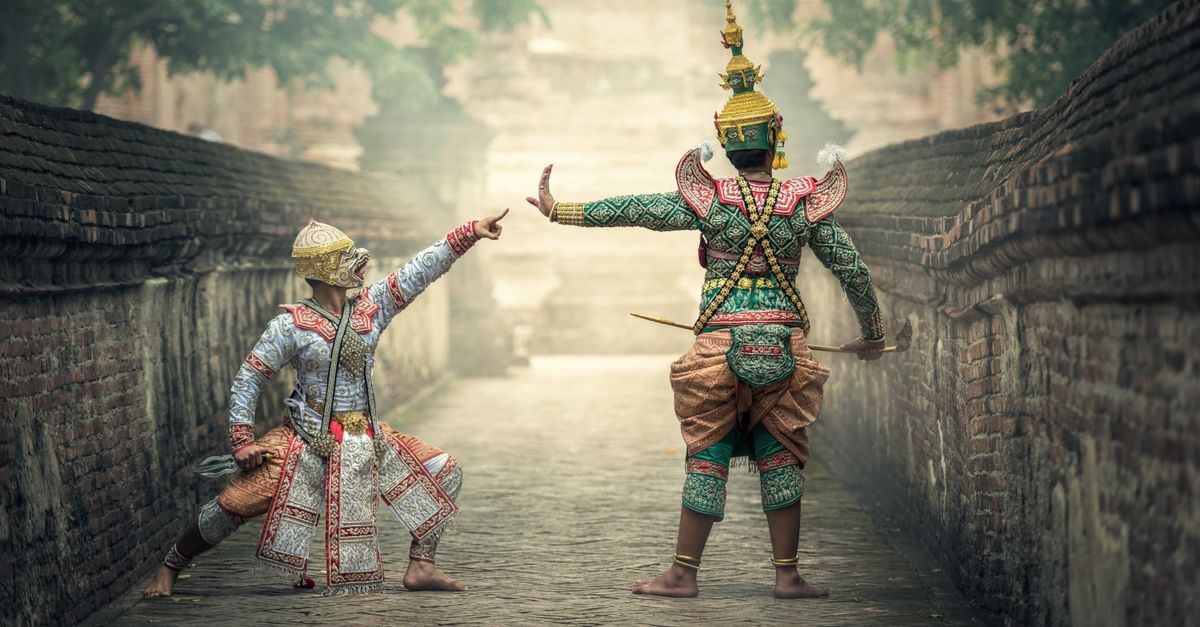 Two performers in vibrant traditional costumes performing a cultural dance outdoors.