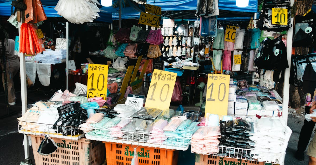 Colorful street market with clothing stalls and sale signs, vibrant and bustling.