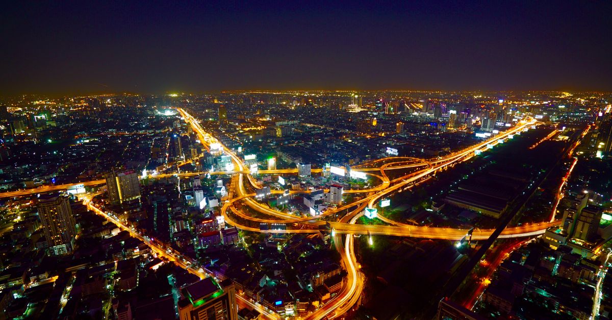 Stunning aerial view of Bangkok's illuminated skyline and busy highways at night.