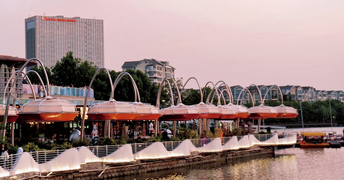 Riverfront promenade with modern dining area lit up at sunset, showcasing urban architecture.