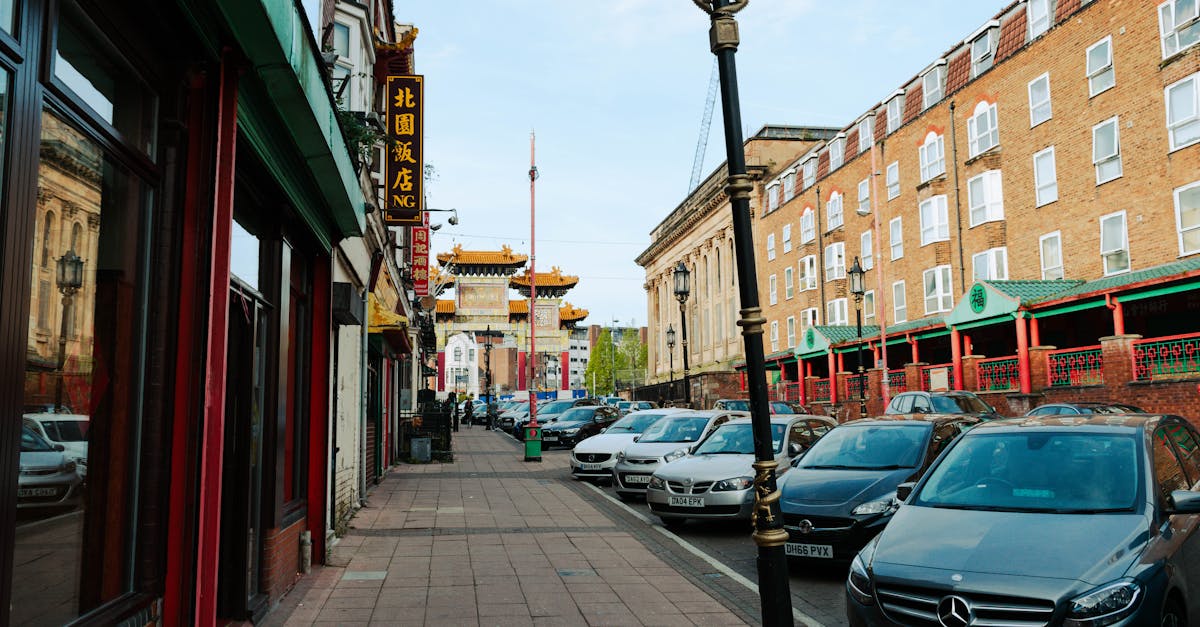 Vibrant street in Liverpool's Chinatown featuring cars, storefronts, and traditional architecture.