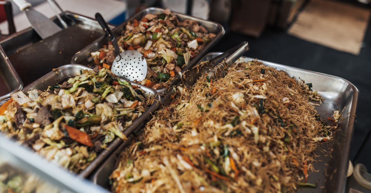 A vibrant street food setup showcasing delicious Asian noodle dishes with vegetables and meat.