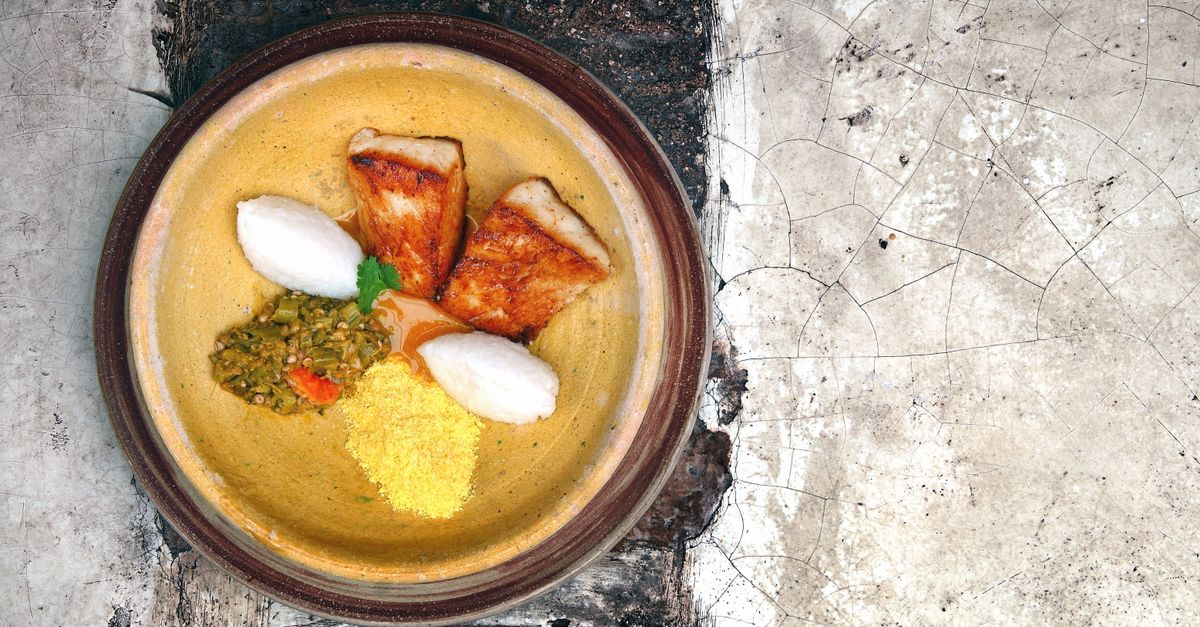 Top view of a traditional fish dish with rice and vegetables on a rustic plate, perfect for food photography.