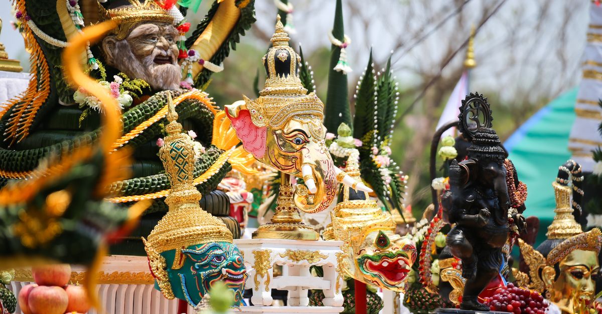 A vibrant display of intricate Buddhist temple figurines and sculptures decorated with gold and colorful adornments.