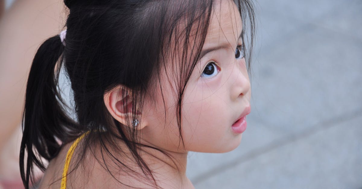 Charming Asian toddler surprised while playing outdoors. Captivating portrait.