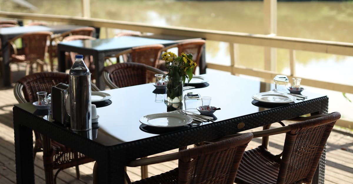 Elegant outdoor cafe table by the river, set for dining with a serene backdrop.