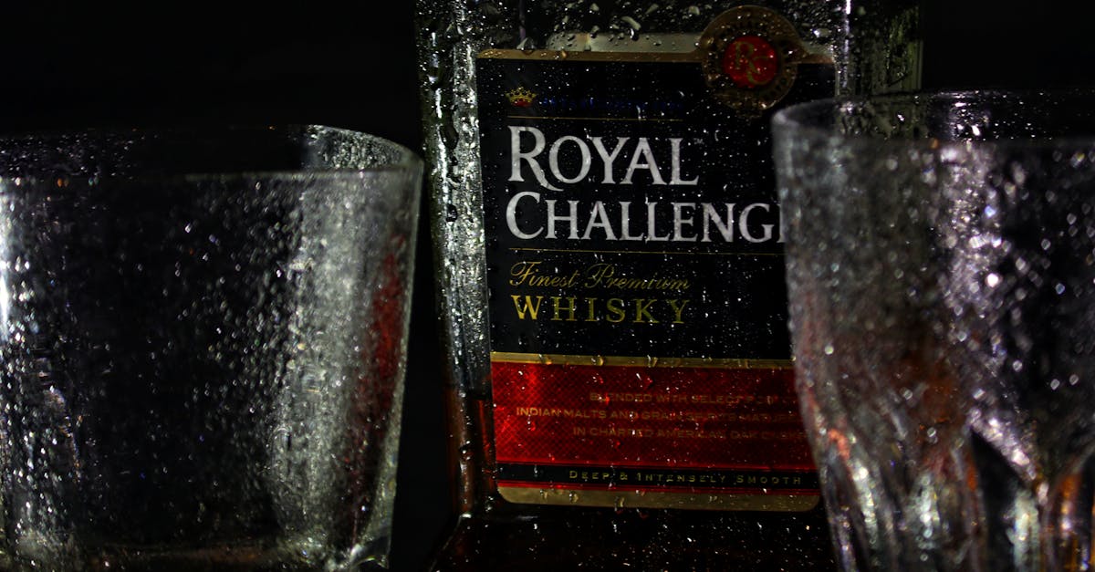 Close-up shot of Royal Challenge whiskey bottle with glasses.