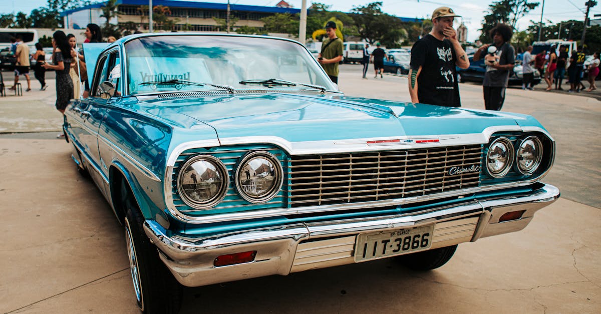 A vintage blue Chevrolet car with chrome details at an outdoor gathering on a sunny day.