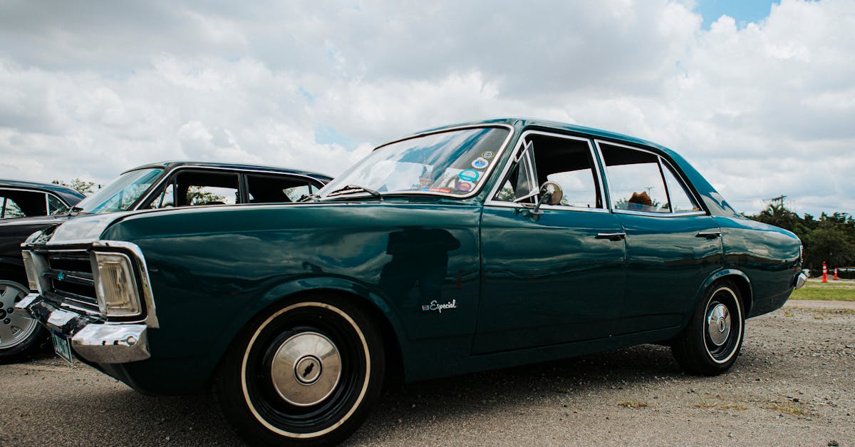 A vintage green car displayed outdoors at a car show on a sunny day.
