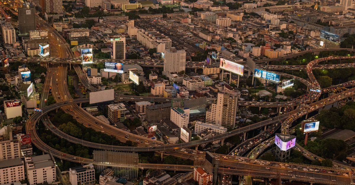 Aerial shot of a busy highway interchange with city skyline at dusk.