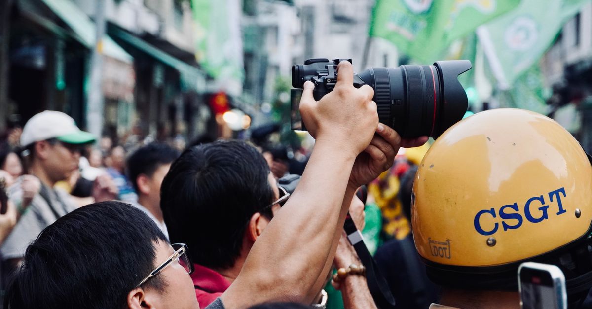 A bustling crowd captures a vibrant outdoor event with cameras in hand.