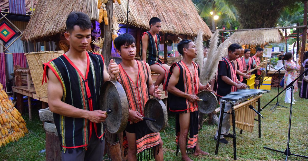 Group of musicians in traditional attire performing with instruments outdoors during a cultural festival.