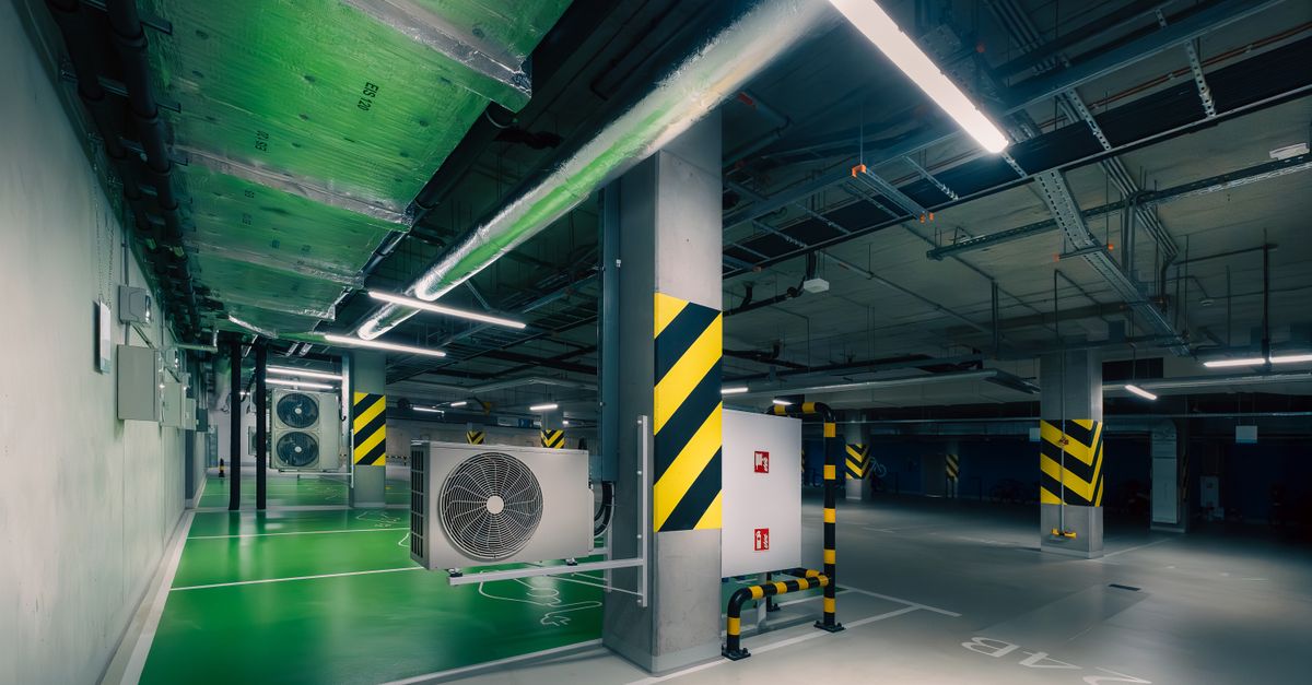 Sleek underground parking area with air conditioning units and green lighting.