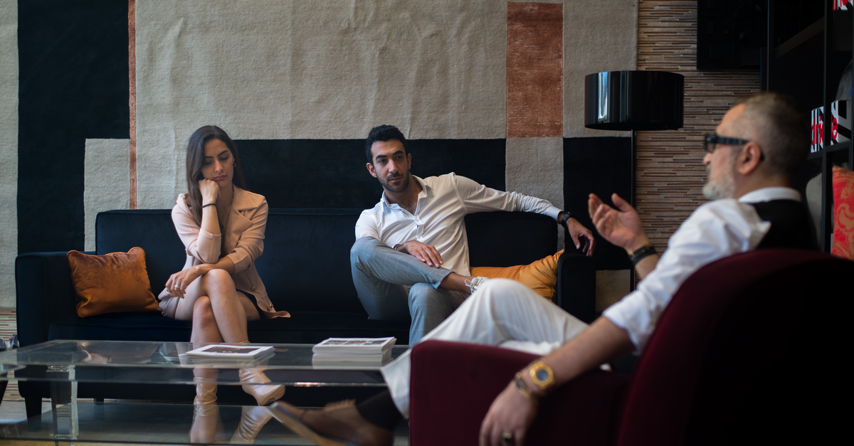 Three adults engaged in a thoughtful therapy session in a stylish Genoa interior.