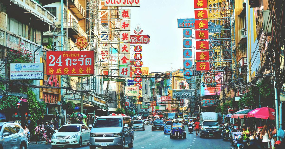 Vibrant cityscape of Bangkok's Chinatown with busy streets and colorful signs.