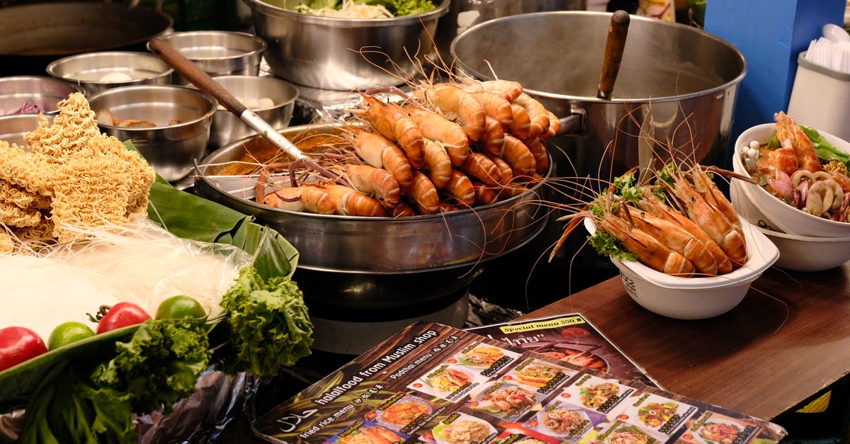 Vibrant display of Thai street food featuring fresh prawns, noodles, and produce.