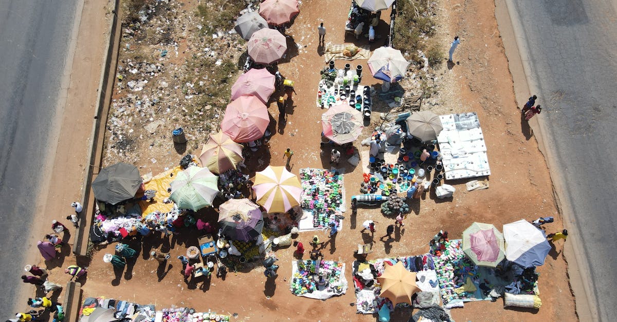 Overhead shot of a vibrant outdoor market with people and colorful umbrellas on a sunny day.