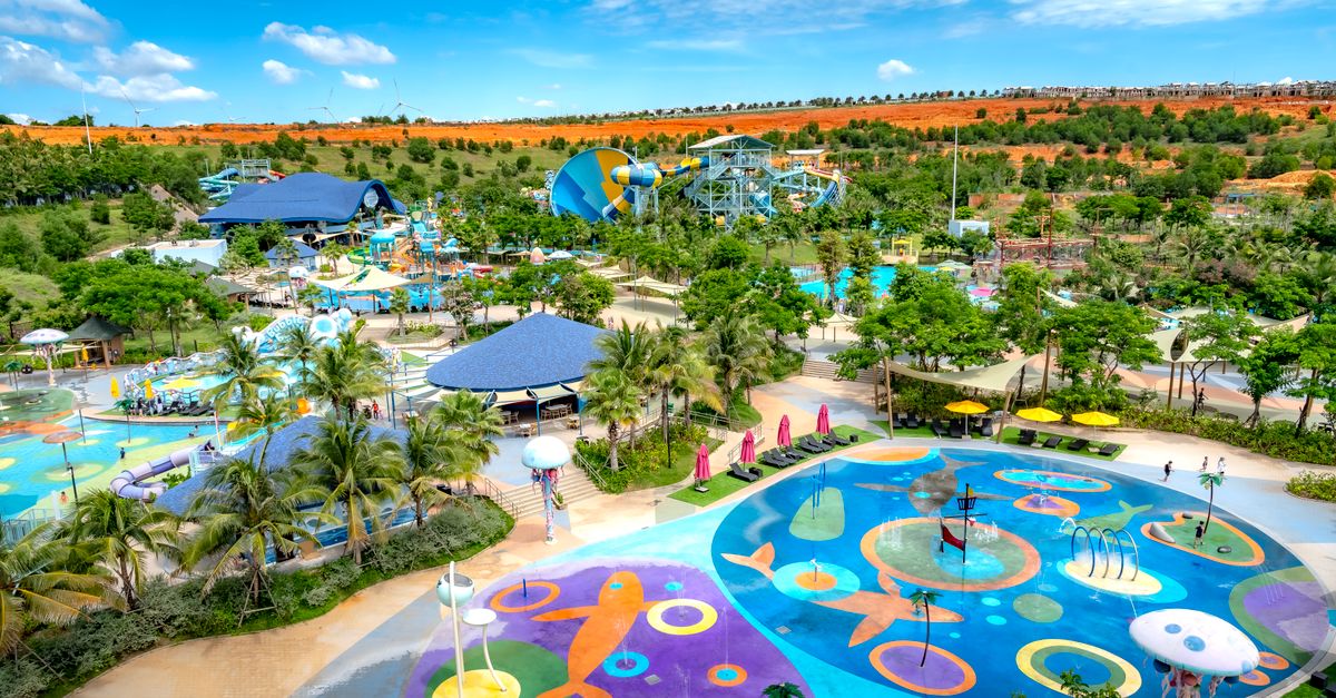 Aerial shot of a colorful and vibrant water park with pools and slides under a sunny sky.