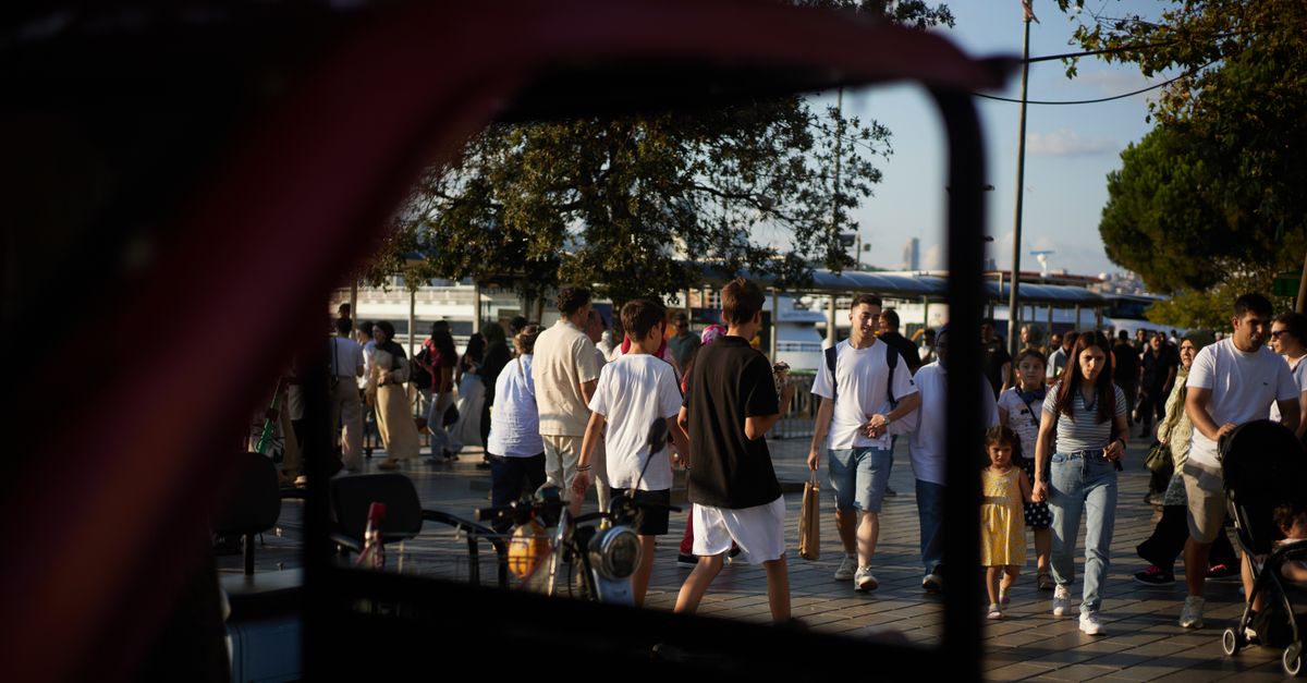 People walking through a lively urban park under sunny skies.