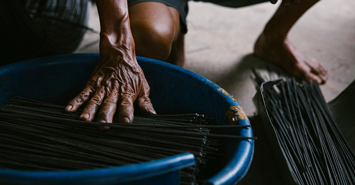 Close-up of an artisan's hands crafting incense sticks in a rustic indoor setting.