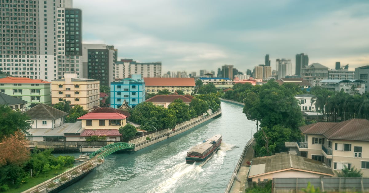 Peaceful canal scene with vibrant buildings and a boat in Bangkok, Thailand.
