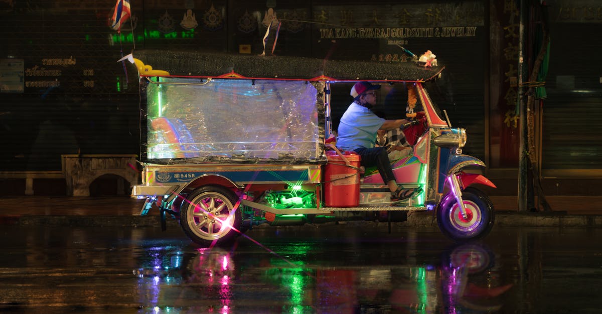 A vibrant tuk-tuk drives through a rainy Bangkok street, reflecting colorful lights.