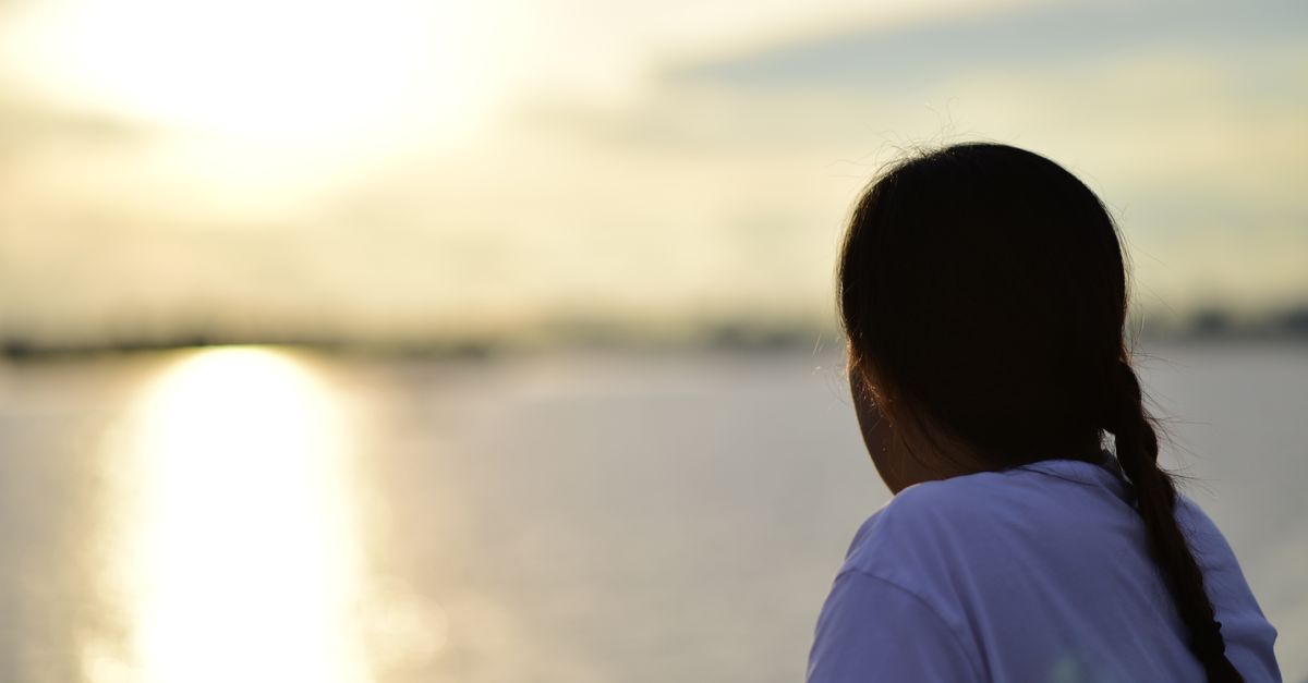 A silhouette of a person gazing at sunset over water. Serene and contemplative mood.