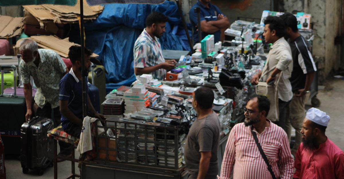 Vibrant market scene with diverse vendors selling electronics under colorful umbrellas.