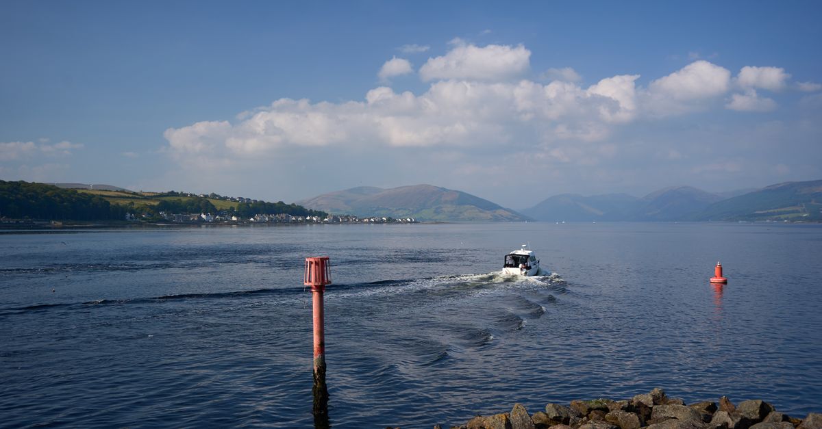 A peaceful scene of a boat navigating through calm waters near the Isle of Bute, Scotland.