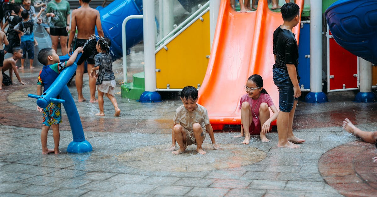 Group of children having fun at a water park in summer, sliding and playing in colorful water playground.
