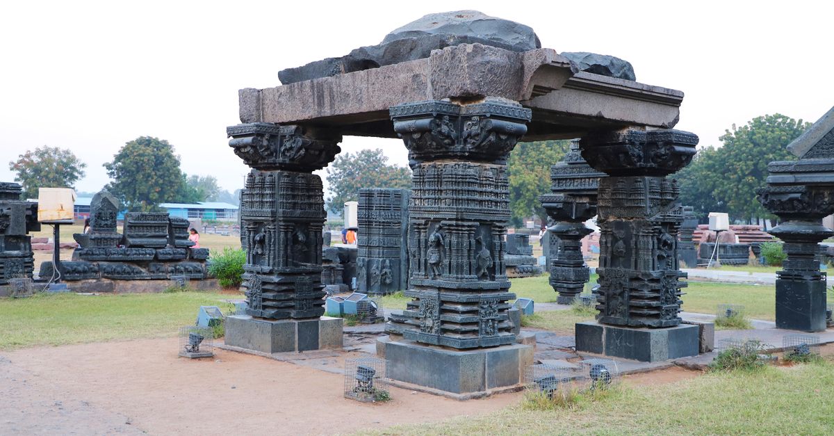 Intricate stone pillar ruins outdoors, showcasing detailed carvings and historic architecture.