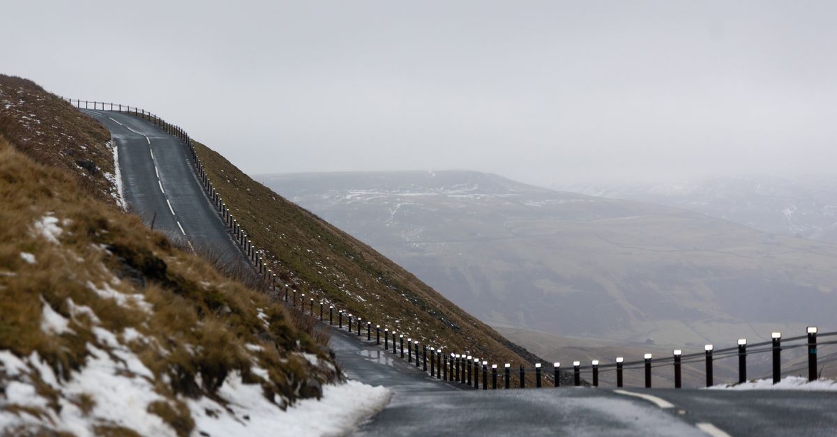 A winding road in snowy Yorkshire Dales, UK under cloudy winter skies promising adventure and exploration.