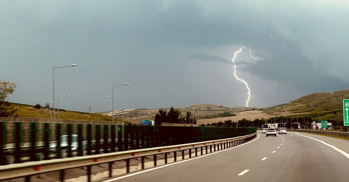 Dramatic lightning storm over a picturesque highway, captured from a moving car.