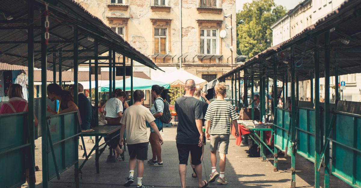 Crowds explore a vibrant outdoor market street in Kraków, Poland.