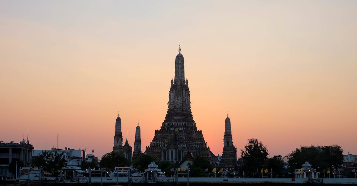 Beautiful sunset view of Wat Arun temple silhouetted against a colorful sky in Bangkok, Thailand.