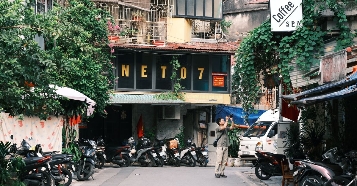 Urban alley with motorbikes and a photographer taking pictures.