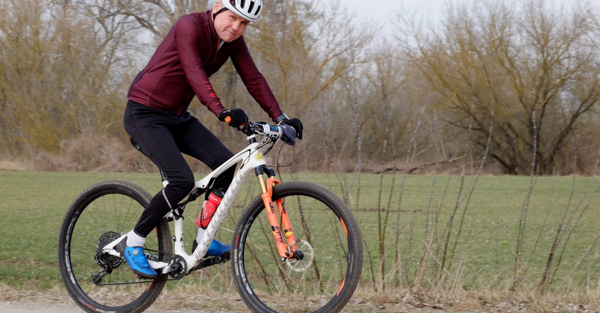 An adult cyclist riding a mountain bike on a gravel path surrounded by nature, showcasing fitness and outdoor activity.
