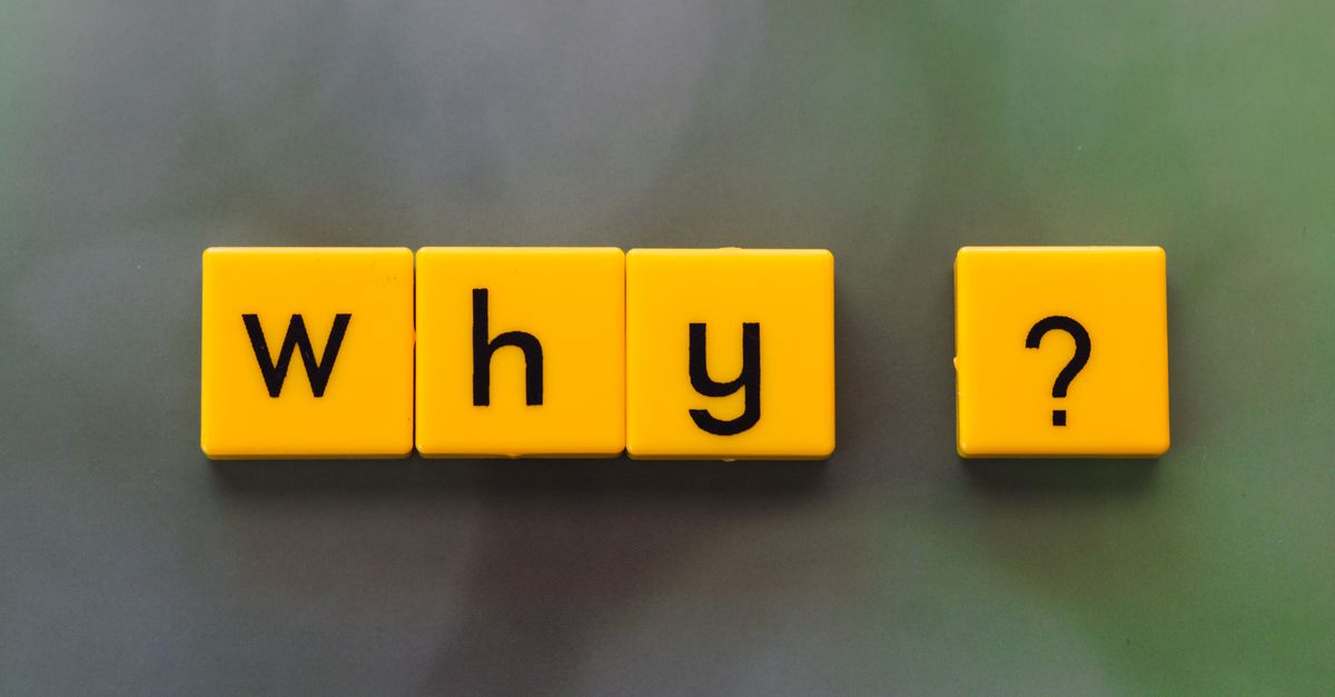 Yellow letter tiles spelling 'why?' create a thought-provoking scene on a green blurred background.