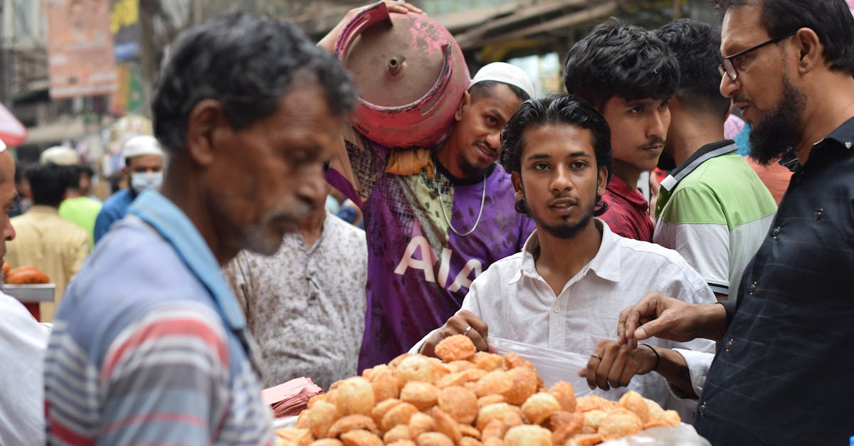Street vendors selling traditional snacks at a bustling Ramadan market in Dhaka, Bangladesh.