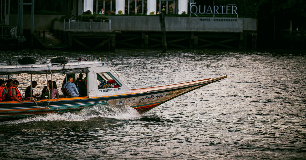 A longtail boat cruises on Bangkok's Chao Phraya River, showcasing Thai culture.