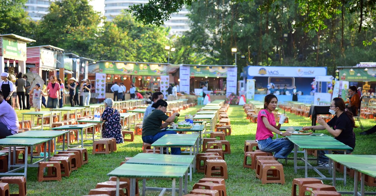 People enjoying an outdoor food festival with various food stalls and dining tables.