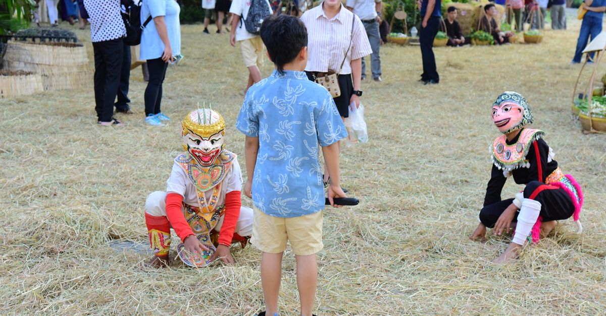 Children interact with masked performers at a lively cultural festival.