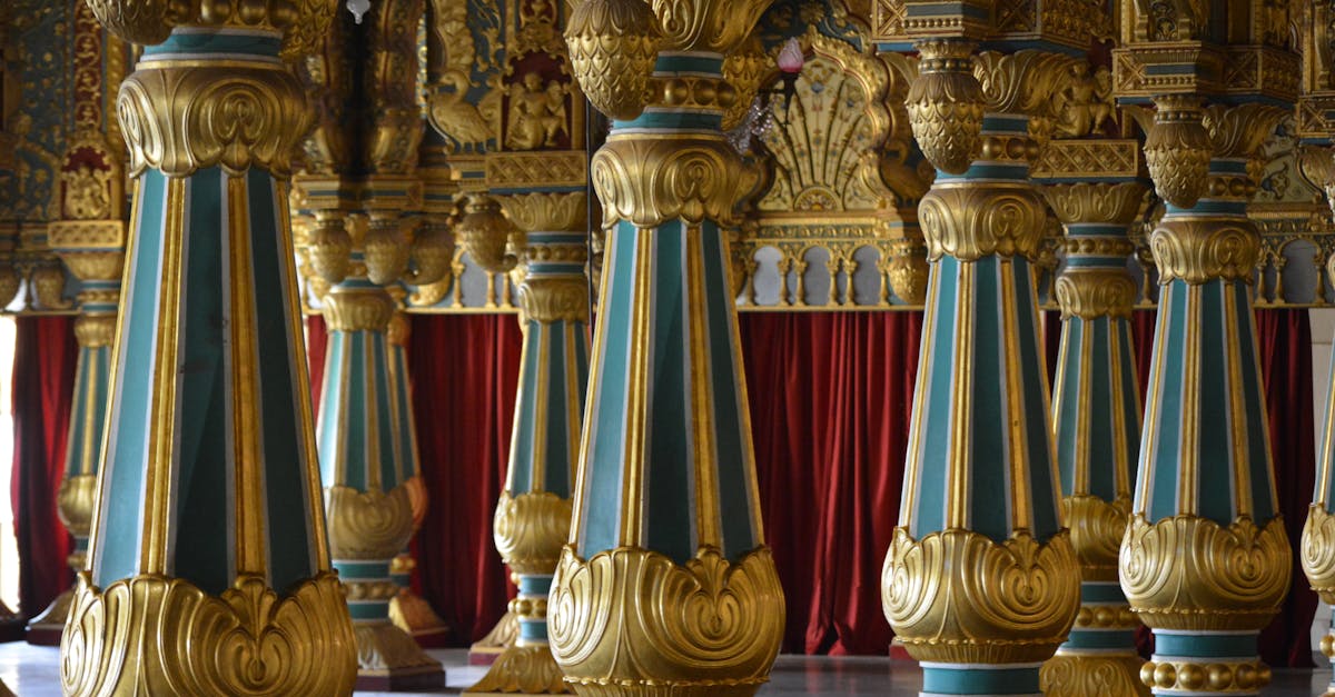 Intricately designed palace columns in gold and blue hues inside a historic royal hall.