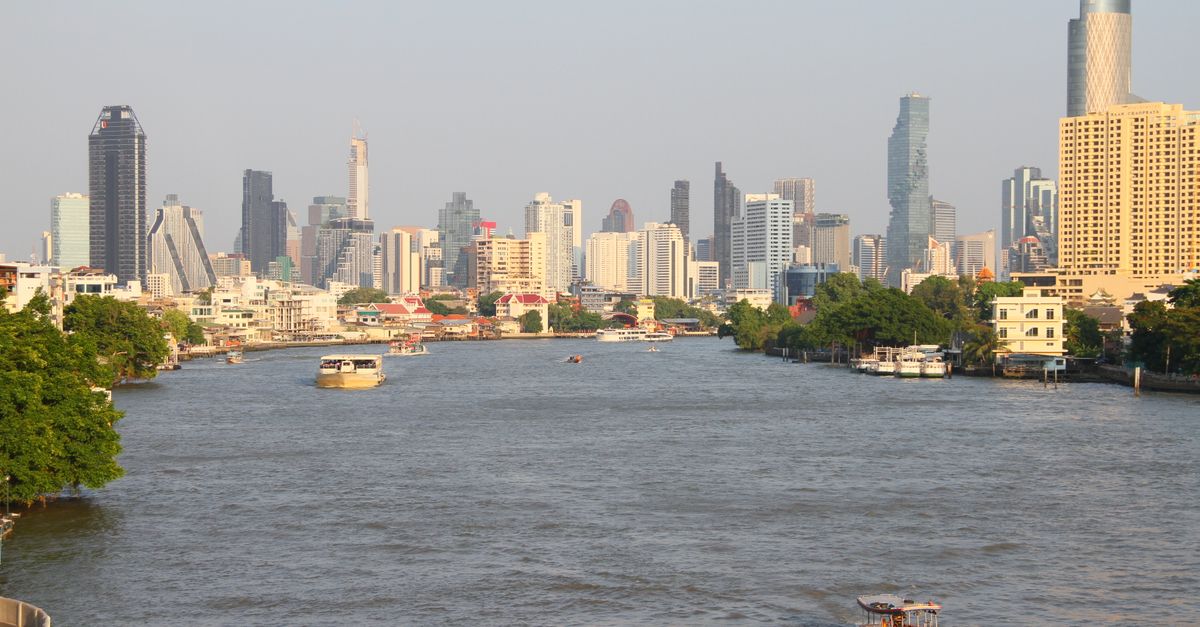 A scenic view of Bangkok's skyline with the Chao Phraya River in the foreground.