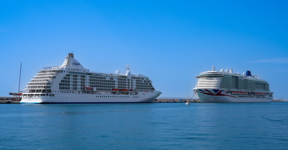 Two large luxury cruise ships docked at Alicante port under a clear blue sky.