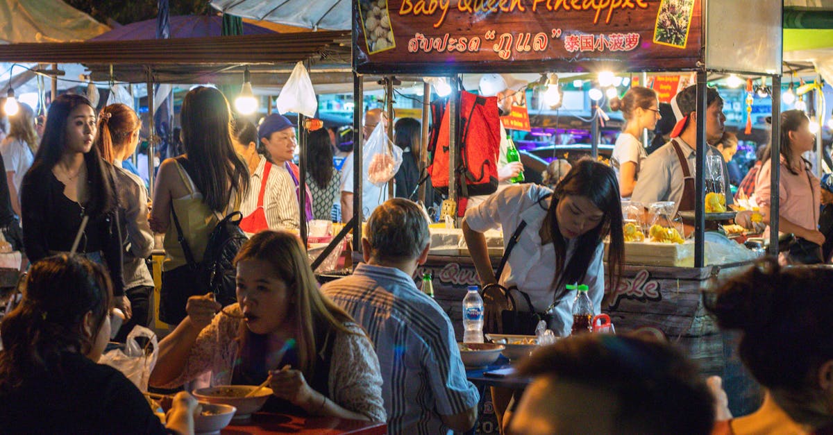 Vibrant night market with busy food stalls and diverse crowd enjoying street food.