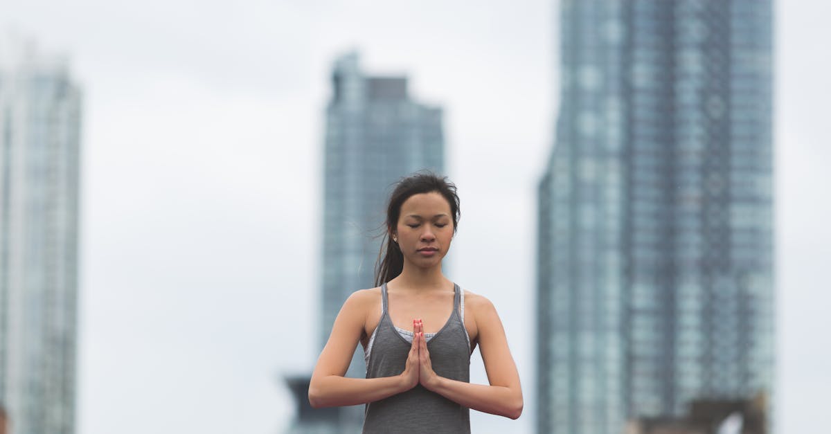 Woman practicing yoga outdoors with city skyscrapers in the background.