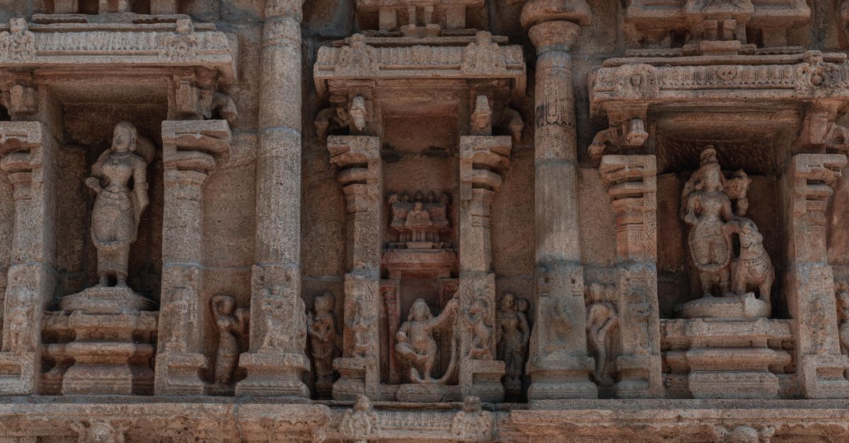 Detailed stone carvings adorn a historic temple facade in Tiruchirappalli, Tamil Nadu, India.