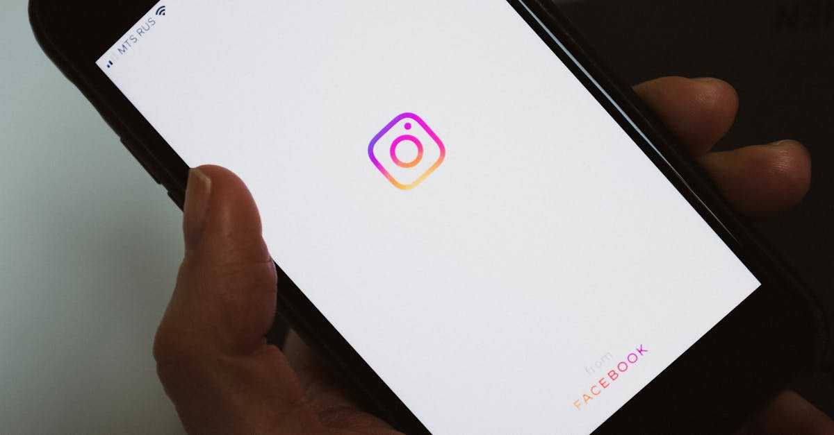 Crop faceless person taking mobile phone and demonstrating blank screen with social media app logo while having break and surfing internet