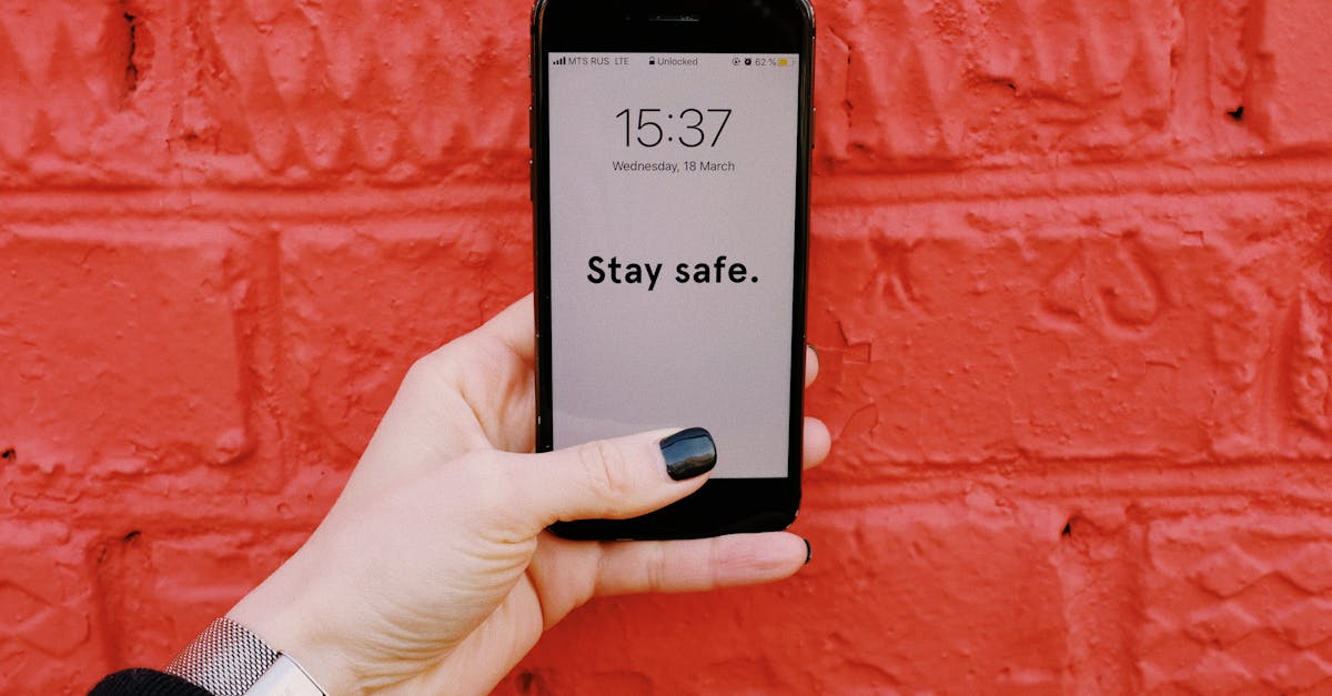 Anonymous crop woman demonstrating smartphone with inscription Stay sage on screen near brick wall painted red